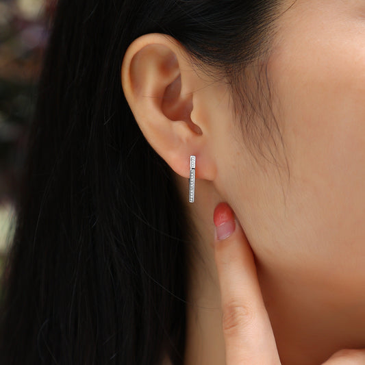 Close-up of an ear wearing a small hoop earring with a blurred background