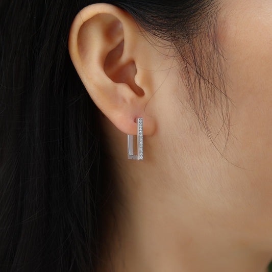 Close-up of an ear wearing a diamond earring with a blurred background