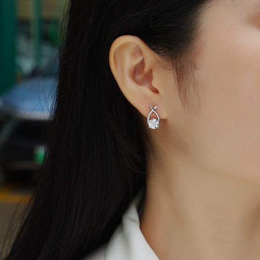 Close-up of a woman wearing a silver earring with a clear gemstone, blurred background