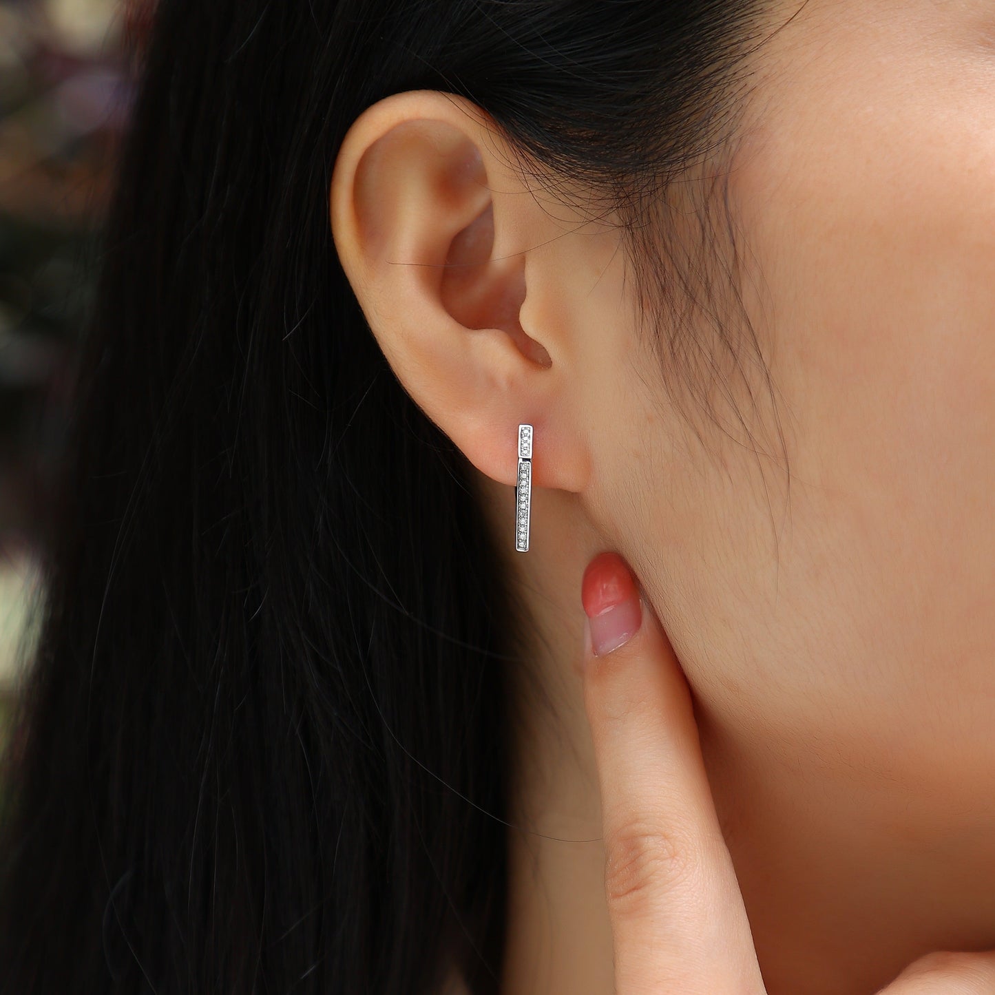 Close-up of an ear wearing a small hoop earring with a blurred background