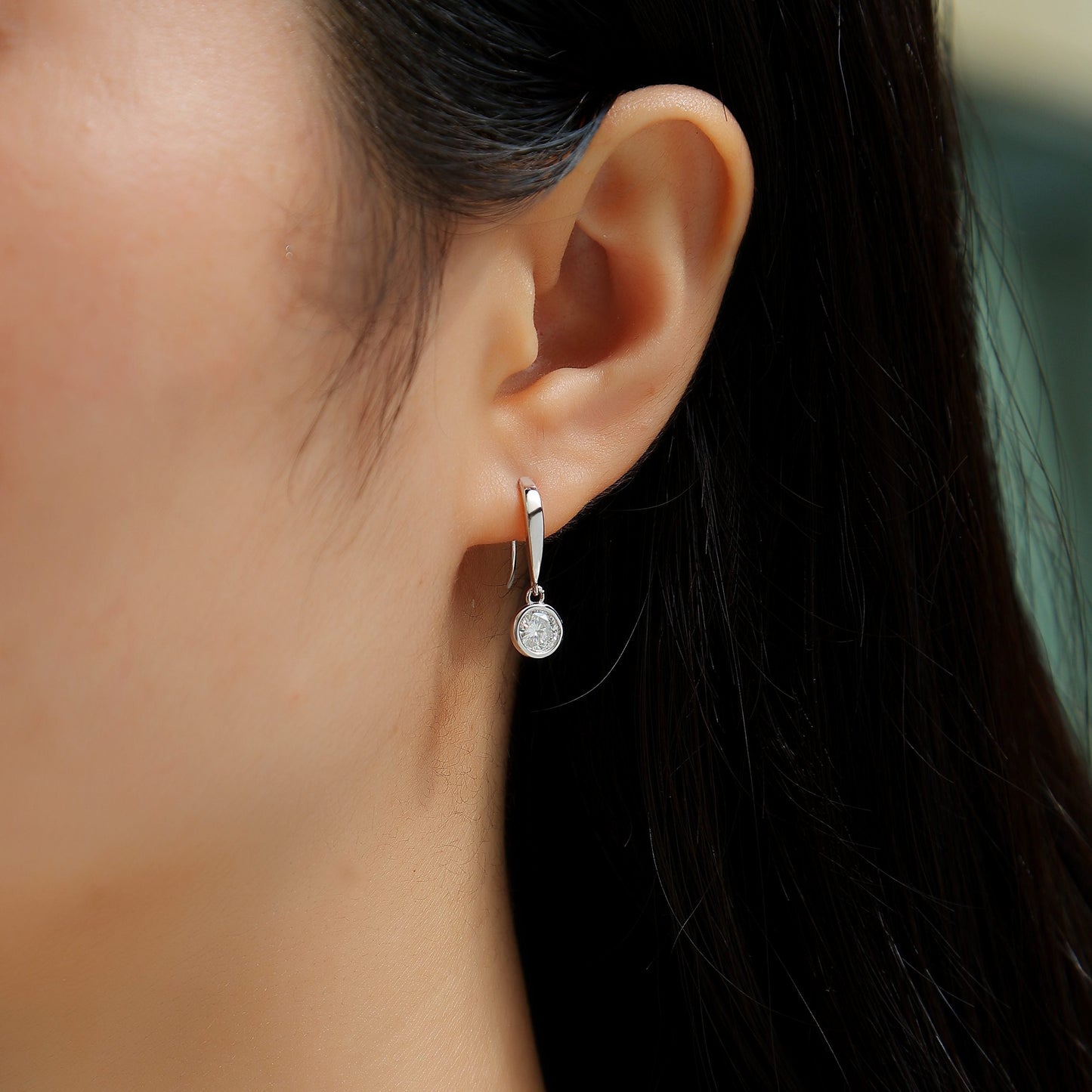 Close-up of a person wearing a pearl earring with a blurred background