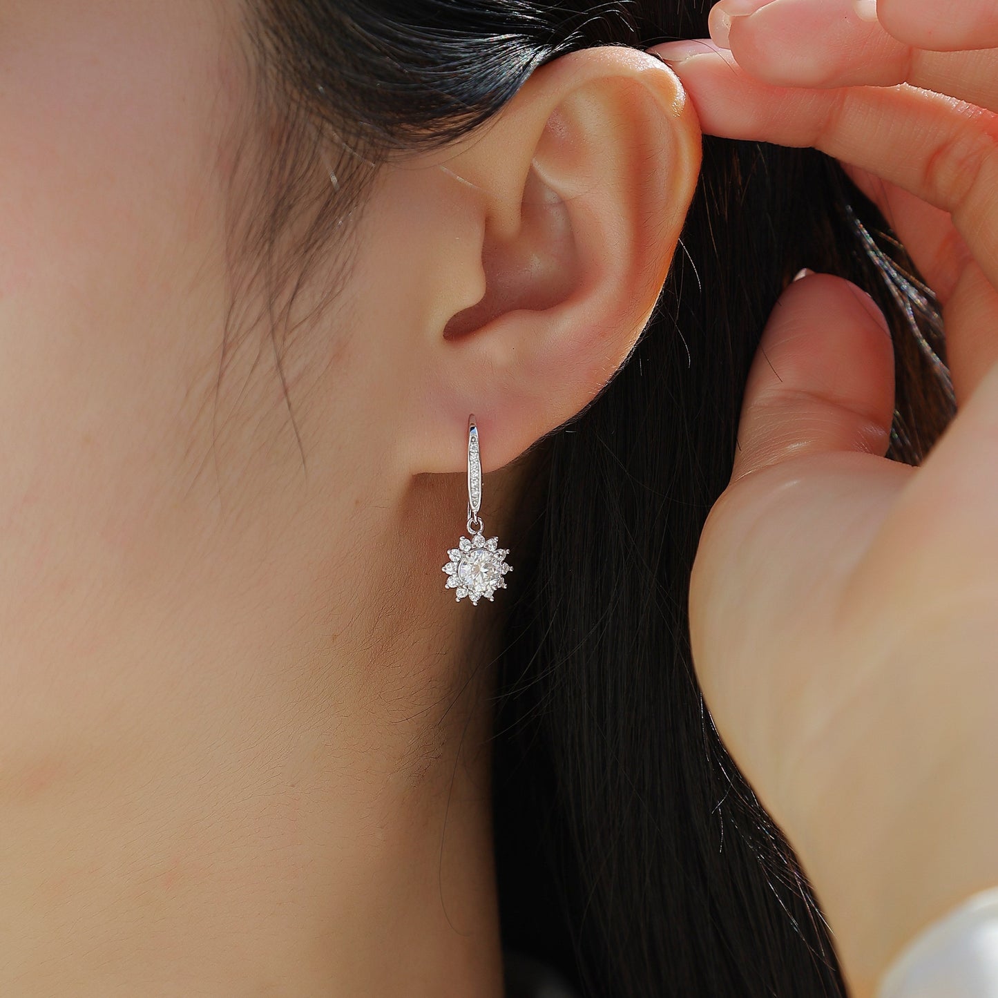 Close-up of a person wearing a silver earring with a star-like design.